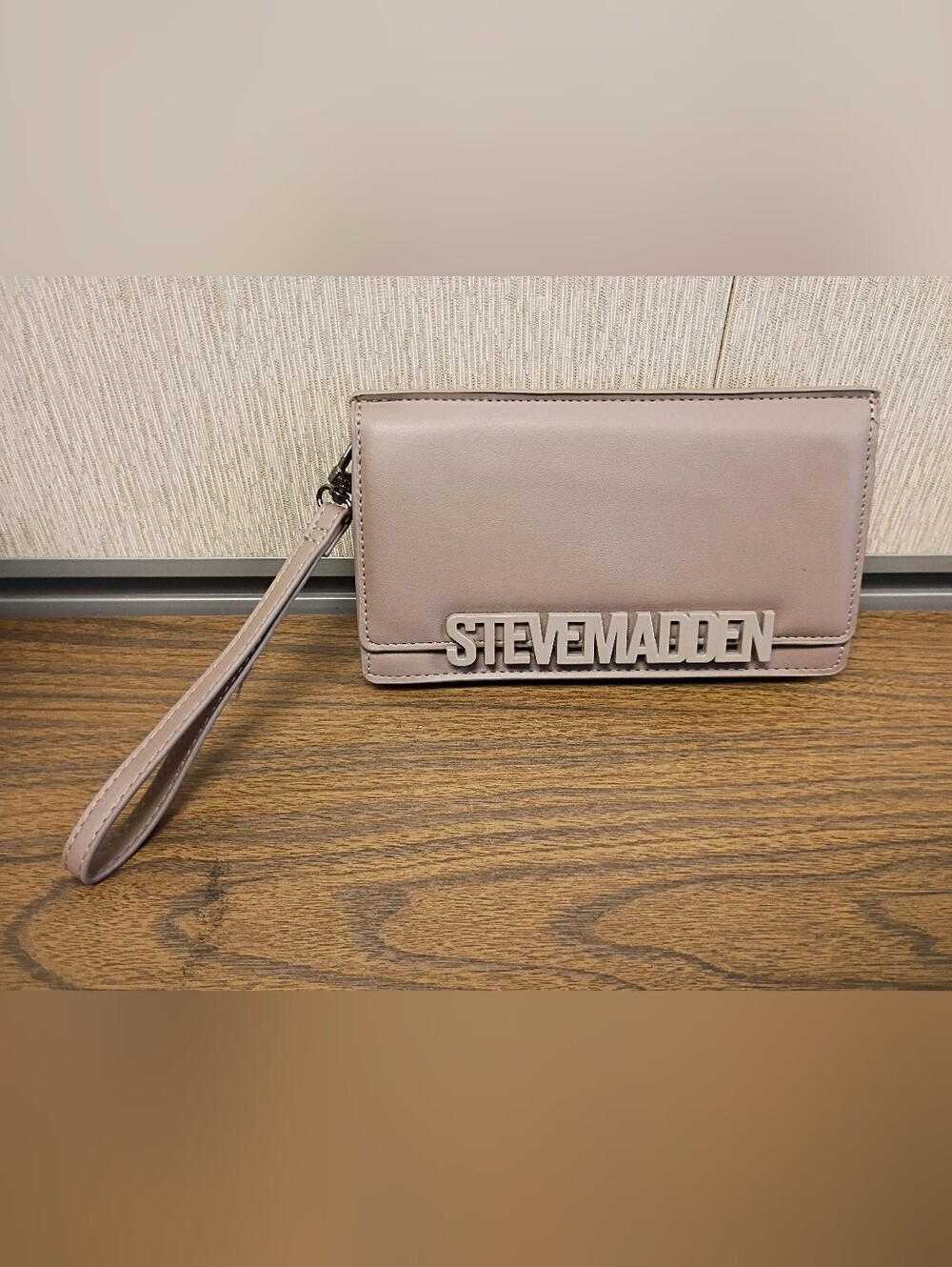 Steve Madden Flap wristlet with a prominent metal brand logo